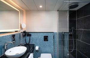 uma casa de banho com um WC, um lavatório e um chuveiro em Leonardo Royal Hotel Frankfurt em Frankfurt