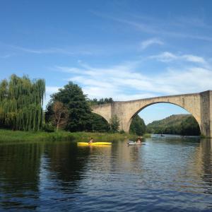 Chambonas的住宿－Terres de France - Le Domaine des Vans，两人在桥下的水上划皮艇