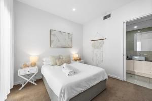 Habitación blanca con cama y baño. en Stylish Home, Family - Walk to Pub,Cafes, 1KM CBD!, en Adelaida
