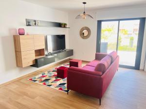 a living room with a red couch and a television at Sevenhouses Pilar de La Horadada in Pilar de la Horadada