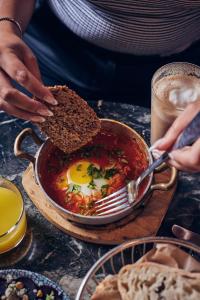 a person holding a piece of bread and a bowl of food at Fabric Hotel - an Atlas Boutique Hotel in Tel Aviv
