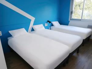 two beds in a room with a blue wall at ibis budget Toulouse Colomiers in Colomiers