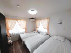 two beds in a room with two windows at 鶴城丸（KAKUJYOMARU） in Karatsu