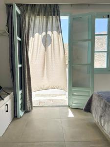 sypialnia z łóżkiem i oknem z zasłoną w obiekcie Folegandros residence/Karavostasi w mieście Karavostasi