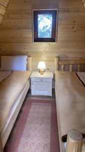 two beds in a log cabin with a window at Eko selo LJUBOTINJ in Cetinje