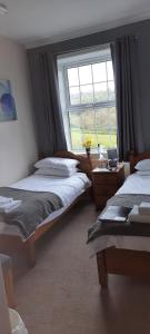 a bedroom with two beds and a window at Arncliffe Arms in Glaisdale