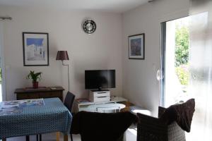 a living room with a table and a tv at Studio RDC Terrasse Repos en Cote d'Armor in Perros-Guirec