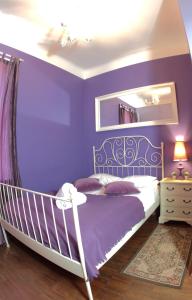 Dormitorio púrpura con cama y espejo en Chmielna Guest House en Varsovia