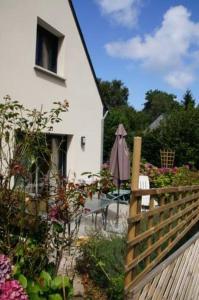 a white house with a fence and a table and an umbrella at Studio RDC Terrasse Repos en Cote d'Armor in Perros-Guirec