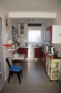 a kitchen with red cabinets and a blue chair in it at Studio RDC Terrasse Repos en Cote d'Armor in Perros-Guirec