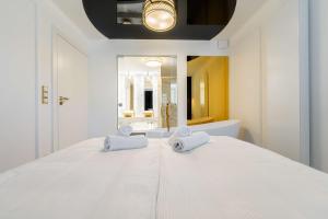 a white bedroom with a large white bed with two towels at Luksusowy Apartament - Plażowa Residence Dream Apart in Szczyrk