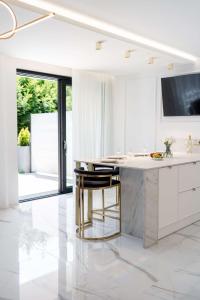 una cucina bianca con un grande bancone in marmo e sgabelli di Luksusowy Apartament - Plażowa Residence Dream Apart a Szczyrk