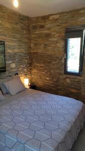 AegeanDeepBlue2 في Apróvaton: غرفة نوم بسرير وجدار حجري +21 صورة