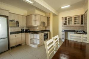 una cucina con armadi in legno, tavolo e sedie di Saints View Resort Unit 22 a Uvongo Beach