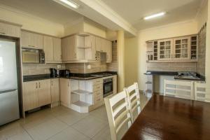 a kitchen with wooden cabinets and a table and chairs at Saints View Resort Unit 22 in Uvongo Beach