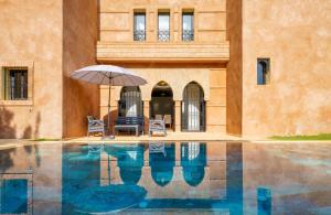 a patio with an umbrella and chairs and a pool at Villa Riad Mamouni - piscine privée et jacuzzi in Marrakech