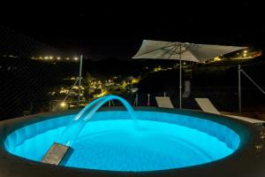 a blue swimming pool at night with an umbrella at Casa Rural La Escalerilla in Teror