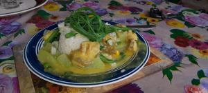 un piatto di cibo con pollo e riso su un tavolo di Yasur View Bungalow and Tree House a White Sands