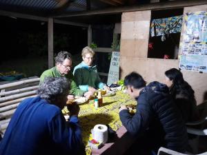 un grupo de personas sentadas alrededor de una mesa comiendo comida en Yasur View Bungalow and Tree House, en White Sands