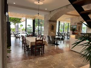 a dining room with tables and chairs and windows at Trevi Hotel & Restorant, Shengjin in Shëngjin
