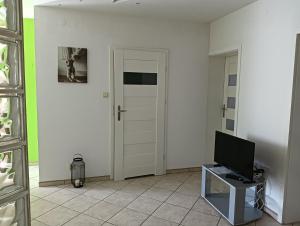 uma sala de estar com televisão e uma porta em Apartament Wyszyńskiego 32m16 em Kalisz