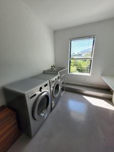 a washing machine in a room with a window at LA HACIENDA - MODERN, BRIGHT, STYLISH House with Private Pool in Cape Town