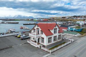 een wit huis met een rood dak naast een haven bij Bjarnabúð in Húsavík