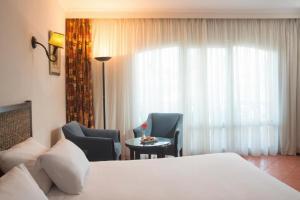 um quarto de hotel com uma cama e cadeiras e uma janela em Porto Sokhna Resort em Ain Sokhna