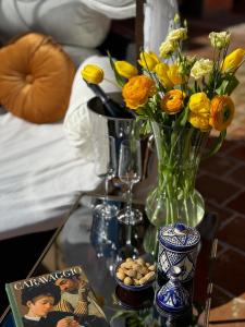 Relais Conac 1888 في Castelnuovo Don Bosco: طاولة زجاجية مع إناء من الزهور ومجلة