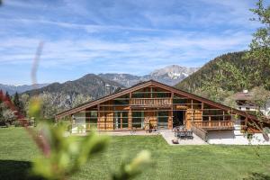 eine große Blockhütte mit Bergen im Hintergrund in der Unterkunft Ferienwohnungen Antenbichllehen in Berchtesgaden