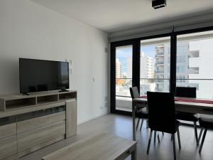 a living room with a television and a table with chairs at Edificio Grimm in Puerto Madryn