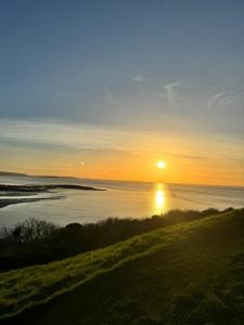 a sunset over the water with the sun in the sky at Garden Place in Clevedon