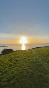 a sunset on a field with the ocean in the background at Garden Place in Clevedon