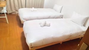 2 Betten mit weißer Bettwäsche in einem Zimmer in der Unterkunft Lite House Shinsaibashi V in Osaka
