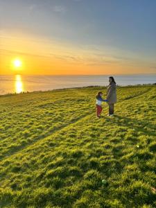 a woman and a child standing in a field at sunset at Garden Place in Clevedon