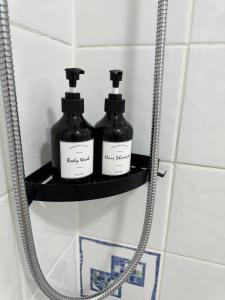 two bottles of soap sitting on a shelf in a bathroom at Garden Place in Clevedon