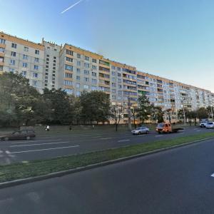 uma rua com carros estacionados em frente a um grande edifício em Studiominsk 15 Apartments em Minsk