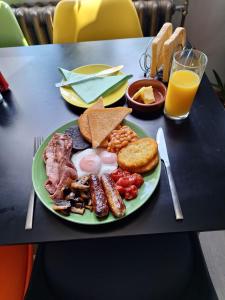 a plate of breakfast food on a table with orange juice at Todmorden Bed & Breakfast - The Toothless Mog in Walsden