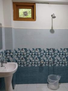 Un baño con lavabo, inodoro y ventana. en Pinewoodschalal, en Kasol