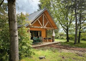 a log cabin in the woods with a porch at Village Huttopia Pays de Condrieu in Tupin-et-Semons