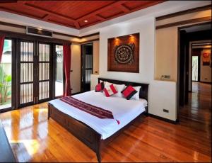 a bedroom with a large white bed with red pillows at Large 4 bed villa short walk to Maenam beach in Mae Nam