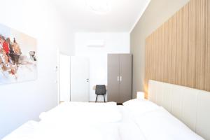 a white bedroom with two beds and a chair at Vienna Stay Apartments or Rooms 1050 in Vienna