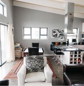a living room with a white chair and a kitchen at 3 Indigo in Hermanus