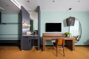 Zimmer mit einem Schreibtisch, einem TV und einem Stuhl in der Unterkunft Van der Valk Hotel A4 Schiphol in Hoofddorp