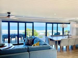 a living room with a couch and a dining room with a view at The Cottage in Morganʼs Bay