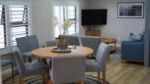 a living room with a table and chairs and a tv at The Cottage in Morganʼs Bay