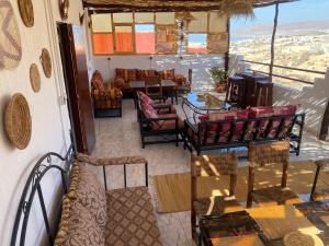 Cette chambre dispose de chaises, de tables et d'un balcon. dans l'établissement Red Carpet Surf Camp, à Tamraght Ouzdar