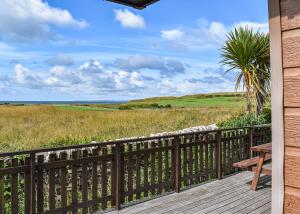 a deck with a bench and a view of the ocean at Brighouse Bay Holiday Park in Kirkcudbright
