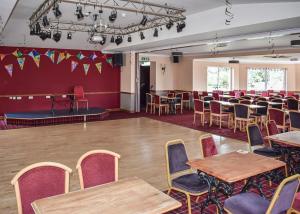 una sala con tavoli e sedie e un palco di Brighouse Bay Holiday Park a Kirkcudbright