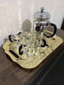 un vasetto di vetro su un piatto con dei bicchieri sopra. di Registan Family Hotel a Samarkand